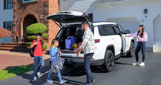 A family putting backpacks into a SUV