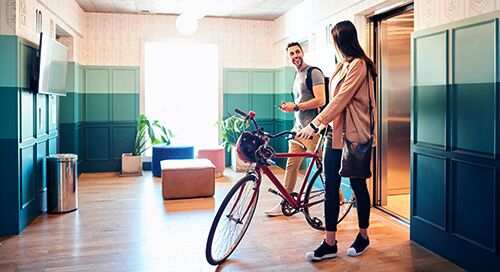 Man and woman talking in a lobby with a bike