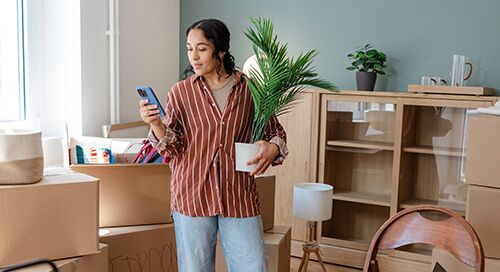 Woman holding a potted plant on her phone