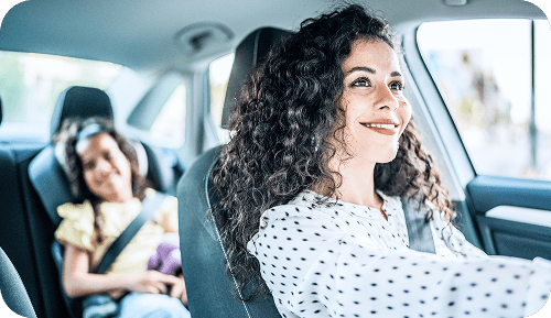 Mother driving car with daughter in child safety seat in back