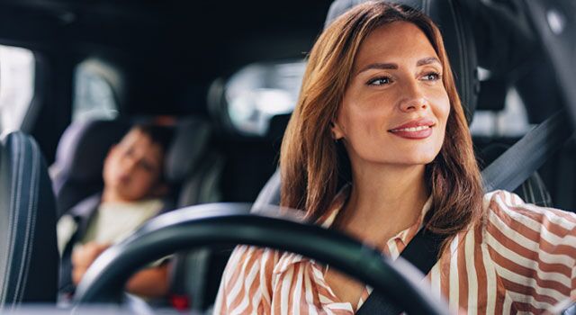 Young mom driving with her son in a child seat