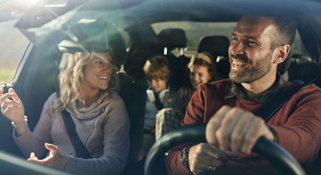 Couple with their children talking and driving