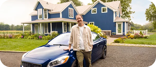 A man standing in front of a blue car and a blue house