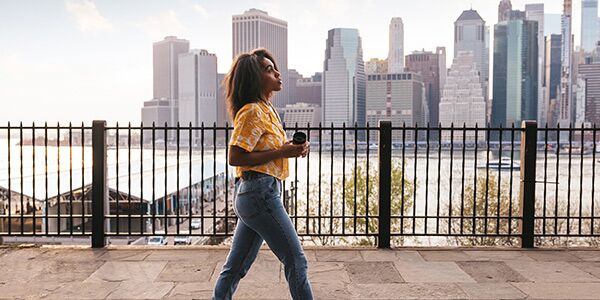 A woman walking with the New York skyline in the background